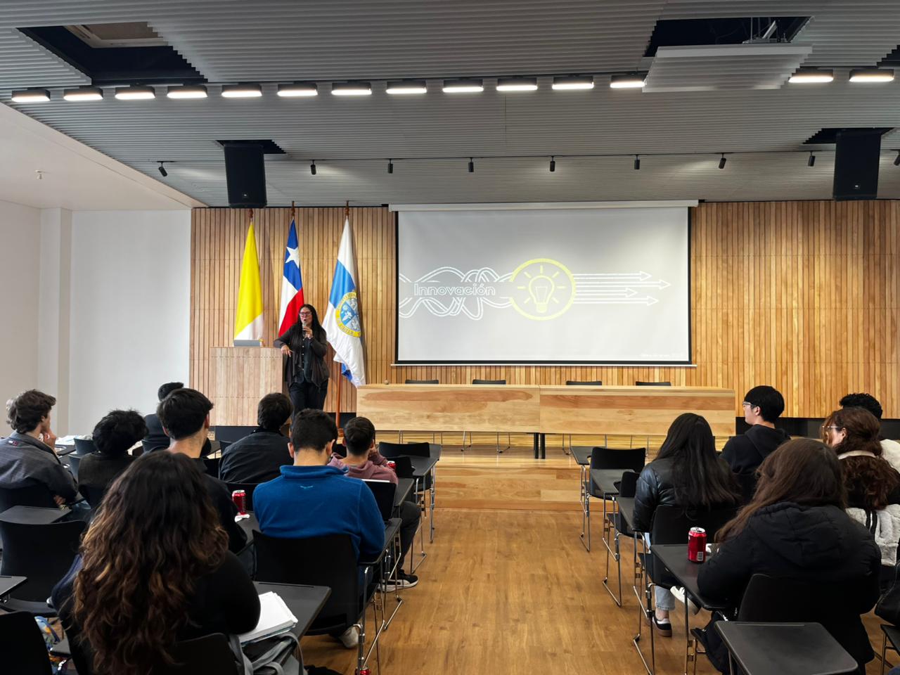 Charla sobre innovación en neurociencia, con presentadora y audiencia atenta en auditorio universitario.
