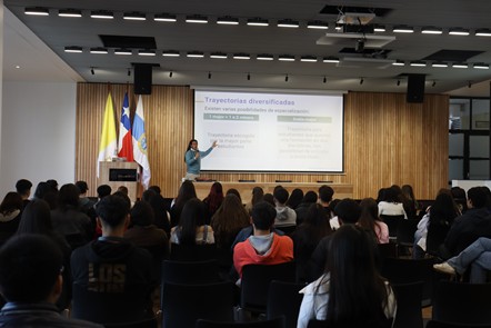 Conferencia sobre trayectorias profesionales con público atento y presentación visual en un auditorio.