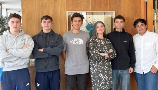 Equipo de seis personas frente a mapa en oficina de Decanato College, mostrando colaboración y ambiente profesional.